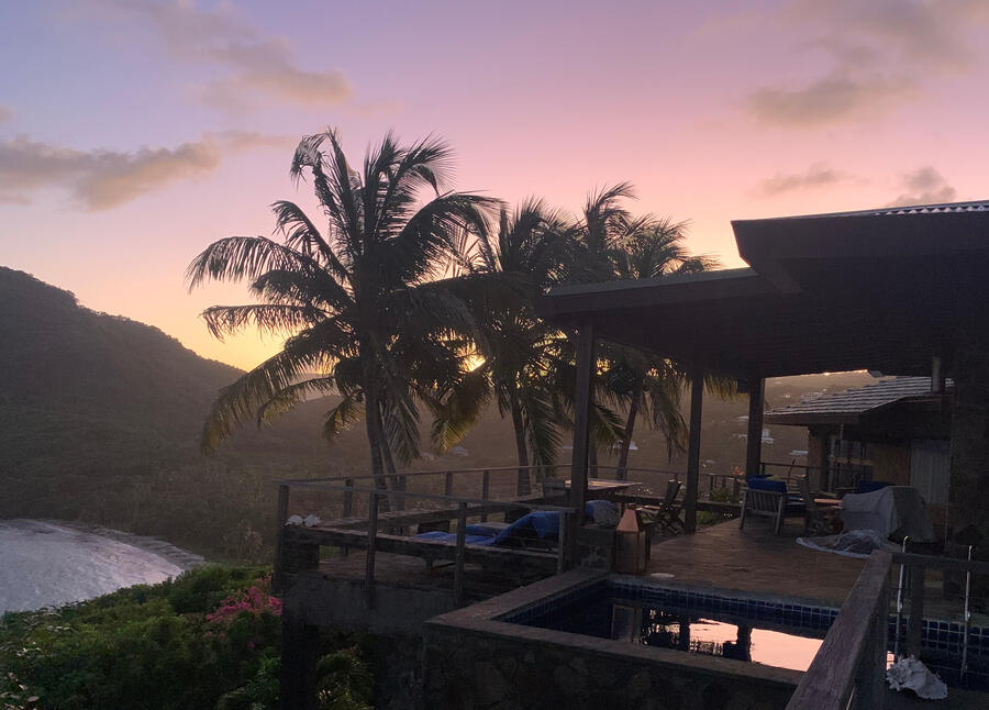 Villa at Sunset View of the plunge pool and deck with coconut palms and pink sky sunset