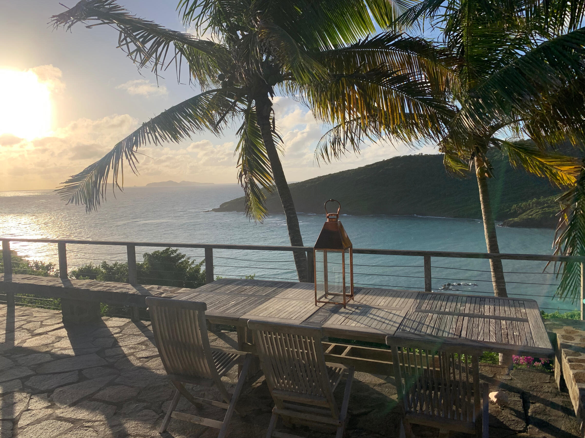 ocean view from main deck view of caribbean water from stone deck with track table and 2 coconut palms